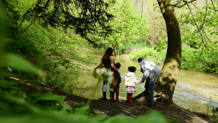 A family standing on the bank and looking across the River Mole at Box Hill, Surrey